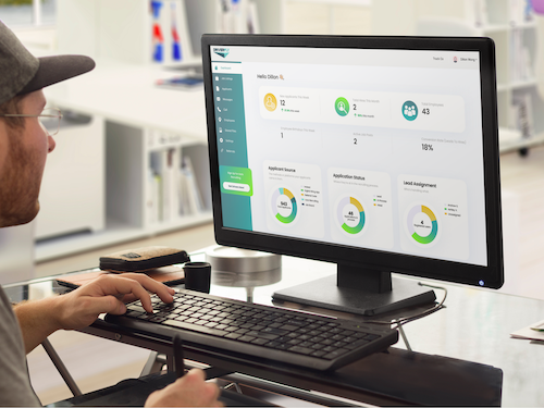 fleet owner in trucker hat at computer using driverfly applicant tracking platform